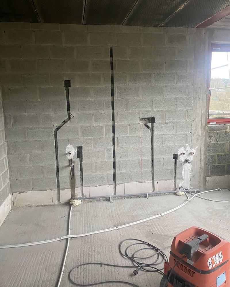 Mur en blocs avec gaines encastrées dans des saignées et boîtiers en attente.
