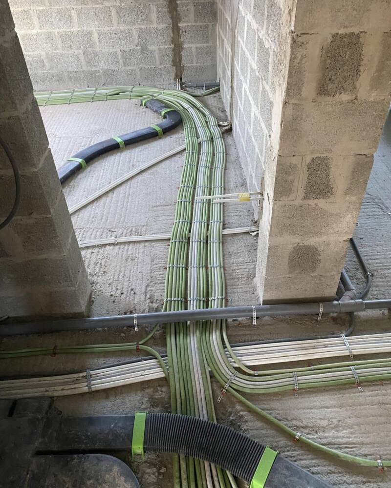 Gaines électriques tirées au sol entre des murs en blocs, avant la chape.