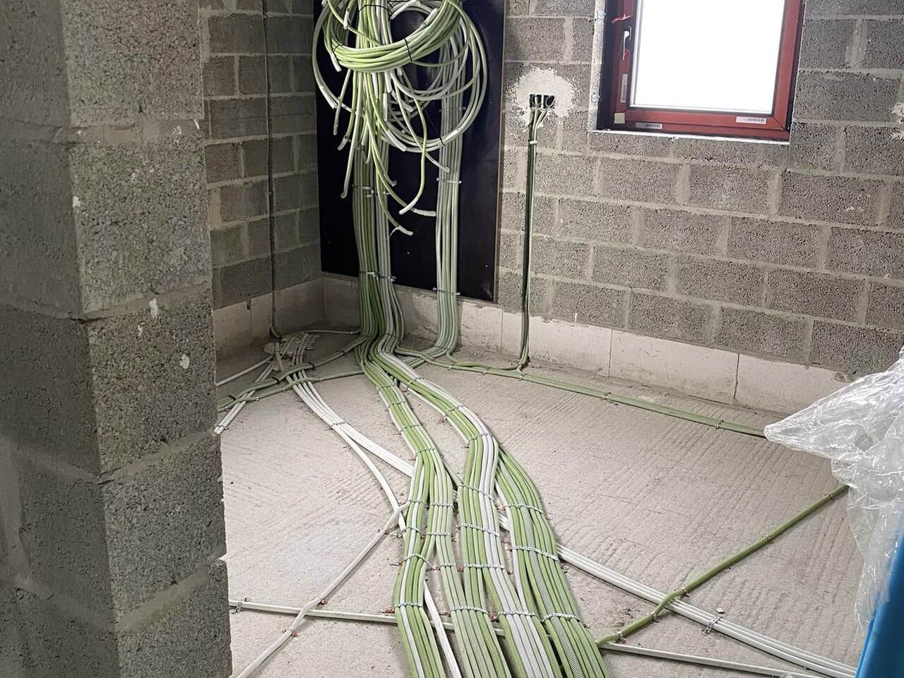 Chantier au stade du gros œuvre : faisceau de câbles électriques en attente, gaines tirées au sol.