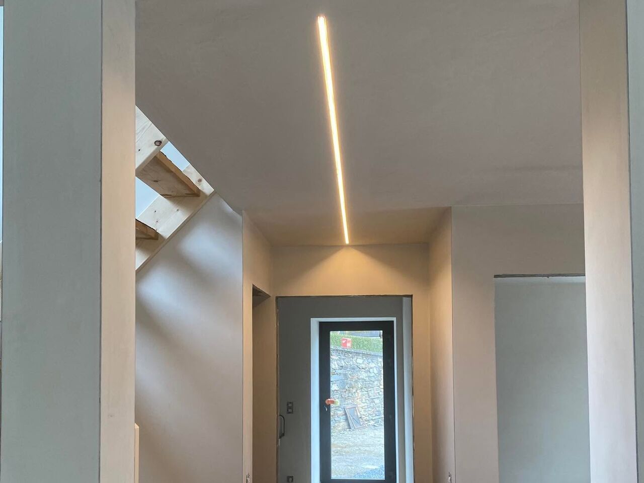 Hall d’entrée lumineux : ruban LED encastré au plafond, couloir et porte vitrée au fond.